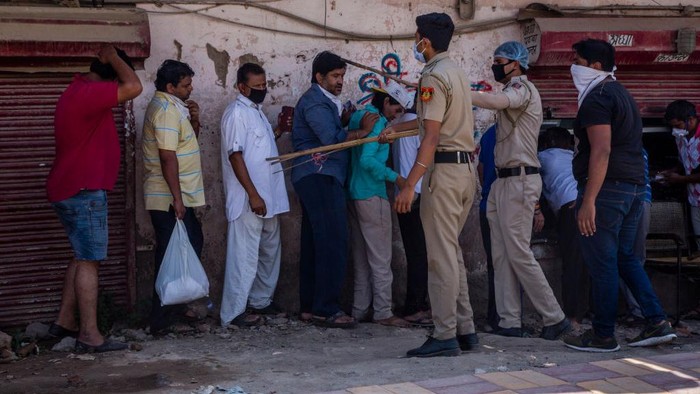 India mulai melonggarkan lockdown. Situasi ini dimanfaatkan warga untuk antre beli miras dengan mengabaikan jaga jarak. Polisi pun memukul warga dengan tongkat.