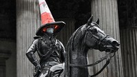 Patung Duke of Wellington bermasker terlihat di luar gedung Galeri Seni Modern, di Glasgow, Skotlandia (29/4/2020). Kerucut cone marka jalan di kepalanya merupakan ulah orang iseng namun dibiarkan saja oleh pengelola galeri dan membuat patung ini lebih dikenal. Jeff J Mitchell/Getty Images.
