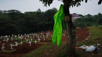 Pakaian APD digantungkan di batang pohon area pemakaman.  