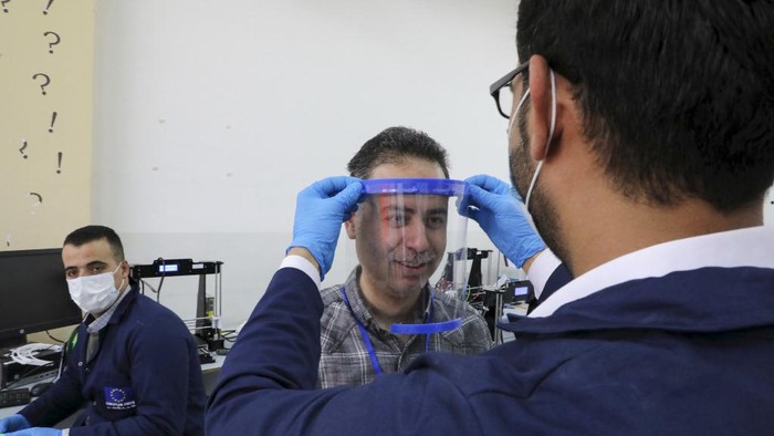 A Palestinian engineer, at the Palestine Polytechnic University in the West Bank town of Hebron, checks the fit of a face-shield that they printed using a 3-D printer on April 21, 2020, as they finalise the design of the shield to help the frontline workers in their effort to combat the spread of the coronavirus (COVID-19). (Photo by HAZEM BADER / AFP)