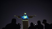 Patung Yesus di Rio de Janeiro memakai masker dengan permainan media laser (3/5/2020). Ia menggunakan kaos bertuliskan Mask Saves dalam bahasa Portugis. AP Photo/Leo Correa.