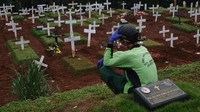 Seorang penggali kubur beristirahat sambil memandangi deretan makam di salah satu TPU di Jakarta.