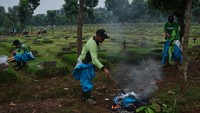 Para penggali kubur membakar pakaian APD yang sebelumnya digunakan untuk membantu memakamkan jenazah korban Corona.