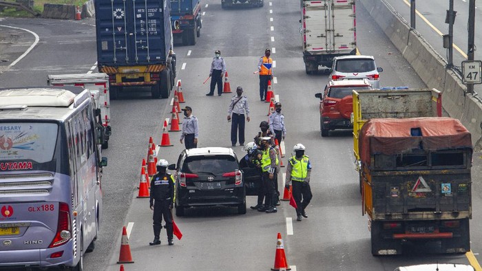 Petugas mengarahkan penumpang kendaraan roda empat untuk melakukan pembatasan sosial atau physical distancing di titik pemeriksaan di Gerbang tol Karawang Barat, Karawang, Jawa Barat, Rabu (6/5/2020). Petugas gabungan memperketat akses keluar masuk kendaraan yang akan melewati gerbang tol pada hari pertama pemberlakuan Pembatasan Sosial Berskala Besar (PSBB) di Karawang. ANTARA FOTO/M Ibnu Chazar/foc.