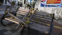warga melintasi bangku trotoar yang disegel di Rawamangun, Jakarta, Selasa (5/5/2020). Bangku-bangku itu telah disegel sejak awal penerapan pembatasan sosial berskala besar (PSBB) pada pertengahan April lalu.