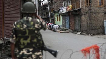 Seorang tentara India berjaga saat muslim Kashmir tengah salat Jumat pada 16 Agustus 2019. AP Photo/Mukhtar Khan.