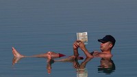 Fakta ini dimanfaatkan oleh wisatawan untuk merasakan sensasi di Laut Mati. Mereka membaca koran sambil mengapung. (Getty Images)