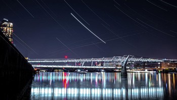 Ini adalah hujan meteor Lyrid di London Millennium Footbridge yang terlihat sangat indah diterangi cahaya bintang-bintang pada malam yang cerah (21/4/2020) di London, Inggris. (Simon Robling/Getty Images)