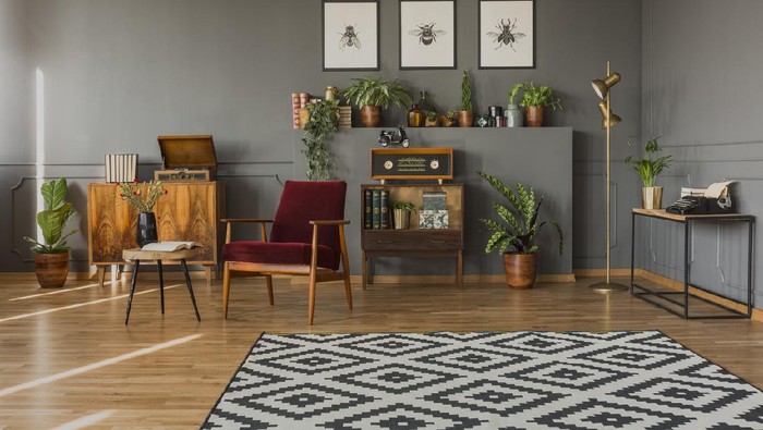 Designer table on brown carpet in front of grey sofa with decorative pillows against tubes in living room
