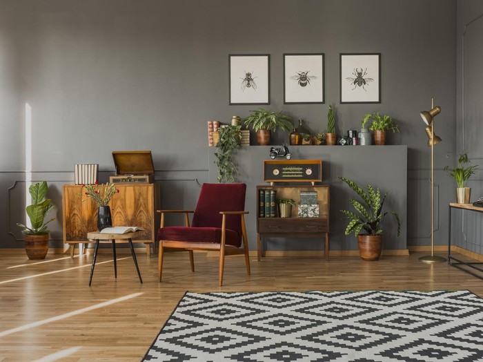 Designer table on brown carpet in front of grey sofa with decorative pillows against tubes in living room