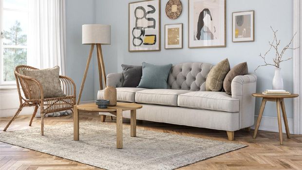 Designer table on brown carpet in front of grey sofa with decorative pillows against tubes in living room