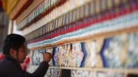 Seorang lelaki Nepal mengecat dinding sebuah biara pada malam ulang tahun kelahiran Buddha di stupa Boudhanath di Kathmandu, Nepal, Rabu, 6 Mei 2020.
