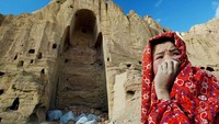  Seorang warga Afghanistan melintas di depan patung Buddha kuno yang telah hancur. Patung Buddha kuno itu hancur setelah diledakkan oleh Taliban. Paula Bronstein/Getty Images.