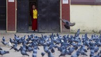 Seorang biksu Buddha melihat keluar dari sebuah biara di stupa Boudhanath pada pada malam ulang tahun kelahiran Buddha di Kathmandu, Nepal, Rabu, 6 Mei 2020. Sebelumnya, sejumlah persiapan jelang Waisak juga digelar para warga. Menurut para pejabat akan ada upacara kecil di sini, di mana ritual akan dilakukan oleh para biksu Buddha.