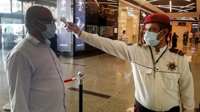 A security guard checks temperature of man arriving at a shopping mall, as a screening precaution against the COVID-19 coronavirus pandemic, in the Saudi capital Riyadh on May 4, 2020, as malls reopen after authorities began a partial lifting of the coronavirus lockdown. (Photo by FAYEZ NURELDINE / AFP)