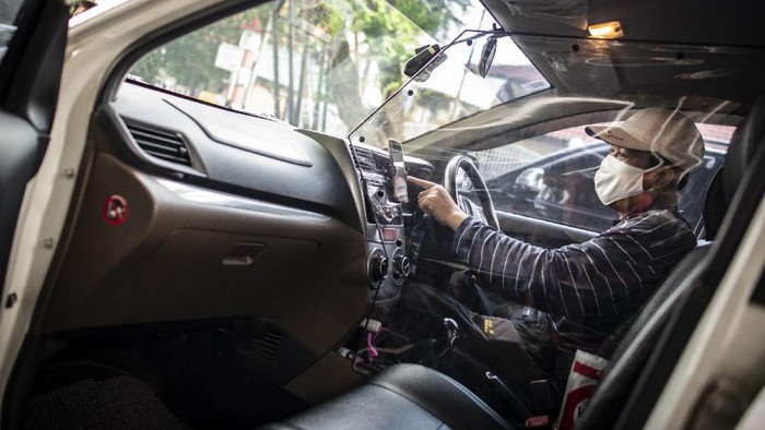 Pengemudi taksi daring, Aris Hardy Halim menunggu calon penumpang di dalam mobilnya yang telah terpasang plastik pembatas di kawasan Bendungan Hilir,  Jakarta, Jumat (8/5/2020). Pemasangan plastik pembatas antara pengemudi dengan penumpang tersebut bertujuan untuk mencegah penyebaran COVID-19 sehingga memberikan kenyamanan dan keamanan kepada pelanggan taksi daring. ANTARA FOTO/Aprillio Akbar/pras.