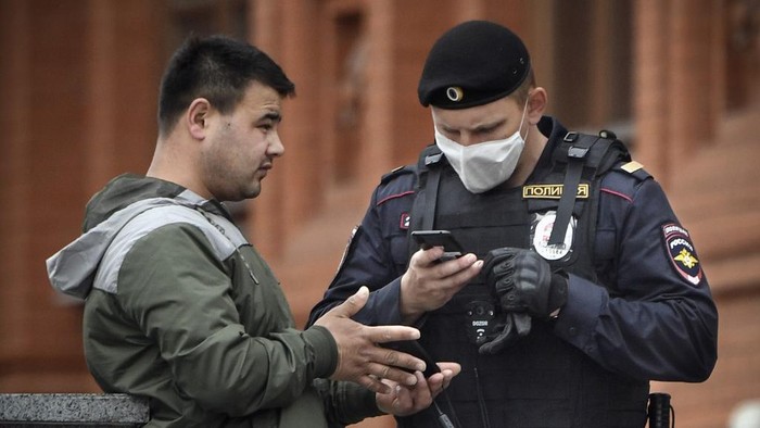A man shows his digital ID to a police officer in downtown Moscow on May 6, 2020, amid the spread of the new coronavirus COVID-19. (Photo by Alexander NEMENOV / AFP)