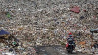 Warga melintas di depan tumpukan sampah di Tempat Pembuangan Akhir (TPA) Rawa Kucing, Kota Tangerang, Banten, yang jumlah volumenmya terus meningkat seiring diberlakukan PSBB di kota tersebut.