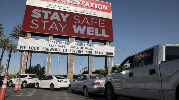 People wait in their cars for food donations at a drive-thru food pantry outside Palace Station hotel and casino on May 7, 2020 in Las Vegas, Nevada. - Michelle Manning pulled up at the Las Vegas casino around 2:30 am feeling confident. She and her sister were not planning to roll dice or play poker at the Palace Station, which like every gambling establishment in the desert city is shut due to coronavirus.  Instead they arrived early enough to beat the six-mile (10-kilometer) line of cars that, each week, snakes around and out the sprawling parking lot, as people wait for the makeshift food bank to open. The site is one of 20 Las Vegas hubs run by Three Square, which sources food from federal government programs, as well as local donors and vendors. (Photo by Bridget BENNETT / AFP)