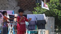 Seorang anak mencoba menerbangkan layang-layangnya saat sedang bermain bersama teman-teman.