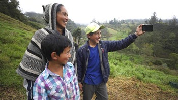 Nubia Rocio Gaona (37) bersama kedua putranya, David (14) dan Alejandro (9) sedang merekam kegiatan mereka melalui kamera ponsel di pekarangan rumah mereka di Chipaque, Kolombia, Sabtu (9/5).