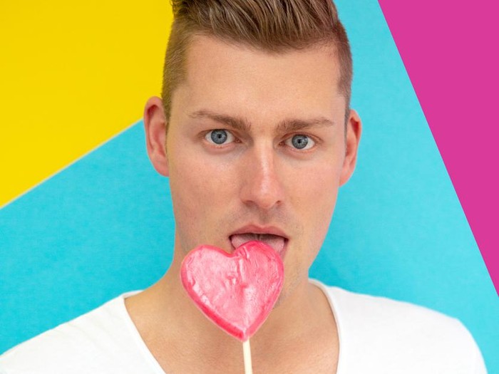 Ilustrasi Lolipop portrait of handsome blond man licking on heart shaped lollipop