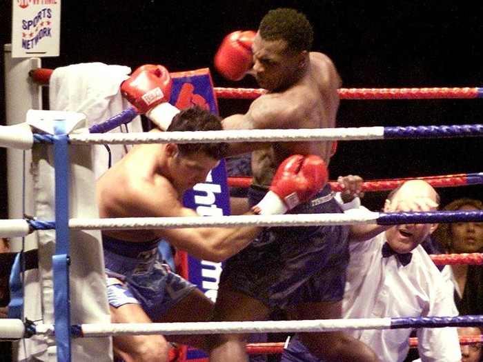 With the referee (R) down on the mat, Mike Tyson (C) lays into Lou Savarese during the first round of their scheduled 10-round bout at Hampden Park in Glasgow 24 June 2000.  Tyson literally went over the referee to finish-off Savarese. (ELECTRONIC IMAGE) (Photo by JONATHAN UTZ / AFP)
