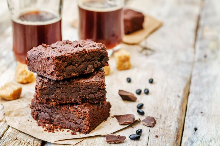 A flourless chocolate cake sits on a cake stand, ready for consumption.