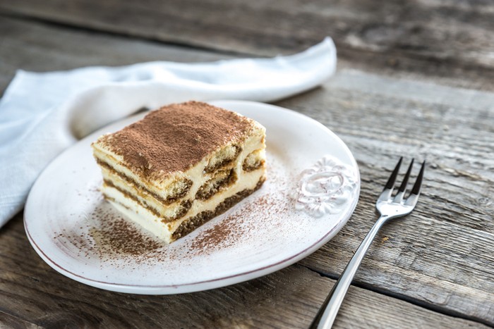A flourless chocolate cake sits on a cake stand, ready for consumption.