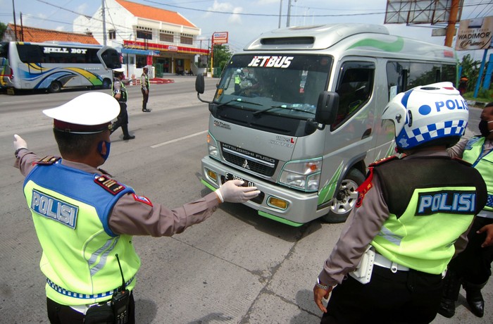 Petugas kepolisian memerintahkan mobil  travel untuk memutar kembali ke arah Jakarta saat penyekatan di jalur Pantura, Tegal, Jawa Tengah, Senin (27/4/2020). Penyekatan kendaraan pemudik oleh Polres Tegal Kota itu dilakukan menyusul adanya larangan mudik oleh Pemerintah guna mencegah penyebaran COVID-19. ANTARA FOTO/Oky Lukmansyah/hp.