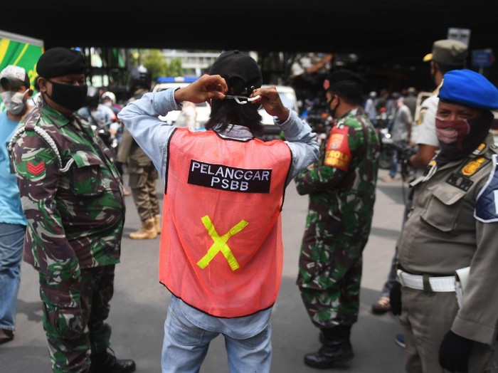 Seorang warga yang terjaring razia penindakan pelanggaran aturan Pembatasan Sosial Berskala Besar (PSBB) oleh Satpol PP menjalani hukuman dengan cara membersihkan sampah di Tanah Abang, Jakarta, Rabu (13/5/2020). Pemprov DKI Jakarta mulai memberlakukan sanksi sosial terhadap pelanggar PSBB yaitu dengan memakaikan rompi bertuliskan pelanggar PSBB saat mereka membersihkan fasilitas umum. ANTARA FOTO/Akbar Nugroho Gumay/aww.
