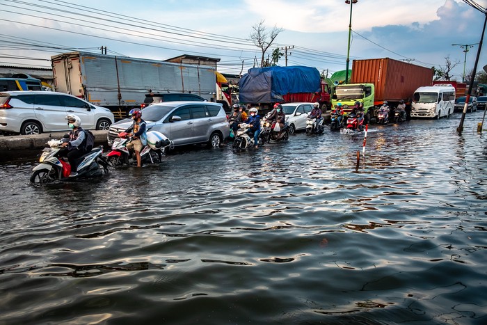 Kendaraan bermotor menembus jalan raya pantura Demak KM 8 ruas Demak-Semarang yang terendam limpasan air laut ke daratan (rob) di Demak, Jawa Tengah, Rabu (13/5/2020). Banjir rob yang melimpas ke jalur utama pantura Demak setinggi sekitar 15-40 sentimeter itu menyebabkan kemacetan lalu lintas sepanjang sekitar 7,5 kilometer dari arah Kabupaten Demak menuju Kota Semarang dan sepanjang sekitar satu kilometer dari arah Kota Semarang menuju Kabupaten Demak. ANTARA FOTO/Aji Styawan/foc.