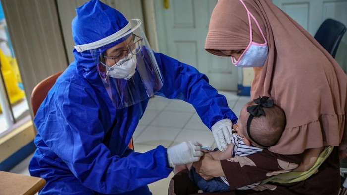 IMUNISASI SAAT PANDEMI COVID-19 Petugas menggunakan alat pelindung diri (APD) memberikan imunsiasi kepada balita di Puskesmas Karawaci Baru, Kota Tangerang, Banten, Rabu (13/5/2020). Pelayanan imunisasi tersebut tetap dilakukan di tengah pandemi COVID-19 demi menjaga kesehatan anak dengan menerapkan protokol kesehatan pencegahan penularan COVID-19. ANTARA FOTO/Fauzan/foc.