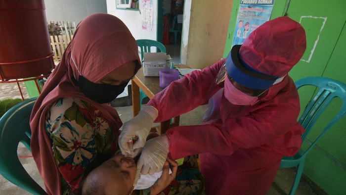 Petugas memberikan vaksin kepada salah satu anak saat imunisasi di salah satu posyandu di Palu, Sulawesi Tengah, Rabu (6/5/2020). Meski tengah dilanda pandemi COVID-19, pelaksanaan imunisasi yang bertujuan untuk menjaga kesehatan anak tersebut tetap berjalan, dengan menerapkan jaga jarak (physical distancing), dilaksanakan pada ruang terbuka serta wajib menggunakan masker. ANTARA FOTO/Mohamad Hamzah/aww.