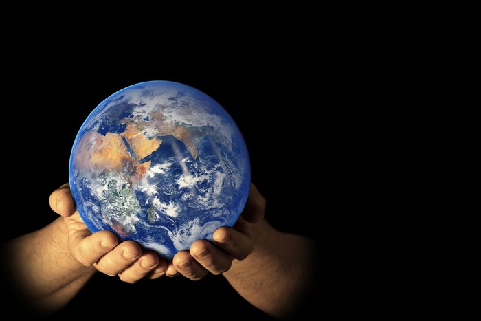 Earth (East view) in male hands isolated on a black background. Space for copy. Earth globe image provided by NASA - https://earthobservatory.nasa.gov/images/84214/blue-marble-eastern-hemisphere
