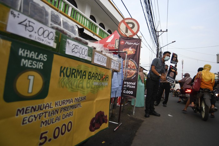 Karyawan salah satu gerai pizza menawarkan produk kepada warga yang melintas di Pondok Betung, Tangerang Selatan, Banten, Rabu (13/5/2020). Ditutupnya sejumlah gerai yang berada di pusat-pusat perbelanjaan imbas dari Pembatasan Sosial Berskala Besar (PSBB), disiasati oleh restoran pizza tersebut dengan melakukan aksi jemput bola ke konsumen sebagai upaya bertahan di tengah pandemi COVID-19. ANTARA FOTO/Puspa Perwitasari/foc.