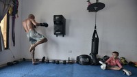 Terlihat seorang atlet Muay Thai yang ditemani anaknya saat melakukan latihan dirumah. Walaupun saat ini beberapa negara telah melonggarkan aturan lockdown secara perlahan. Gabriel Aponte/Getty Images.