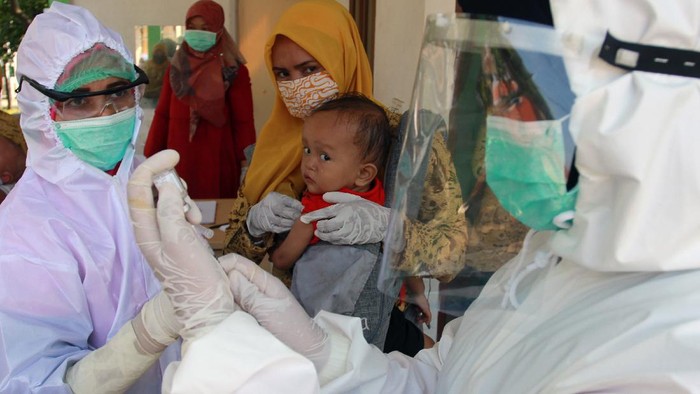 Dua petugas medis dengan alat pelindung diri (APD) dari Puskesmas Babakan bersiap memberikan suntikan imunisasi kepada seorang balita di Posbindu Cempaka 2 Babakan, Tangerang Selatan, Banten, Selasa (12/5/2020). Pelayanan imuniasi tersebut untuk menjaga kesehatan anak walaupun di masa pandemi COVID-19, dengan mengedepankan protokol kesehatan pencegahaan penularaan COVID-19 saat memberikan pelayanan. ANTARA FOTO/Muhammad Iqbal/foc.