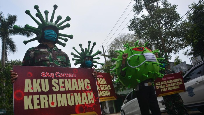 SOSIALISASI PENGGUNAAN MASKER CEGAH COVID-19 Anggota TNI dan Polri menggunakan helm menyerupai bentuk virus Corona saat sosialisasi penggunaan masker di Jalan KH Wahid Hasyim, Kabupaten Jombang, Jawa Timur, Jumat (17/4/2020). Polisi bersama TNI di Kabupaten Jombang mengimbau agar masyarakat tetap tinggal di rumah dan selalu mengenakan masker saat beraktivitas di luar untuk memutus rantai penyebaran virus COVID-19. ANTARA FOTO/Syaiful Arif/wsj.
