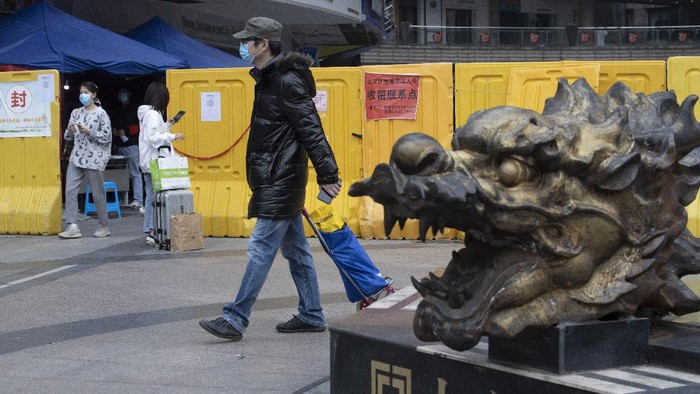 In this photo taken Sunday, April 5, 2020, residents walk near a sealed off neighborhood in Wuhan, central Chinas Hubei province. Authorities in Wuhan, the Chinese city where the coronavirus pandemic first broke out, have reportedly launched a plan to test everyone in the city of 11 million people in the next 10 days. (AP Photo/Ng Han Guan)