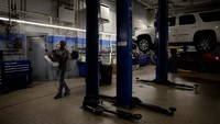 Elliot Nelson menyemprotkan disinfektan pada sebuah toko reparasi mobil di Kansas, AS.