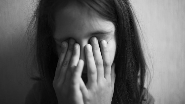 Little girl covers her face with hands isolated