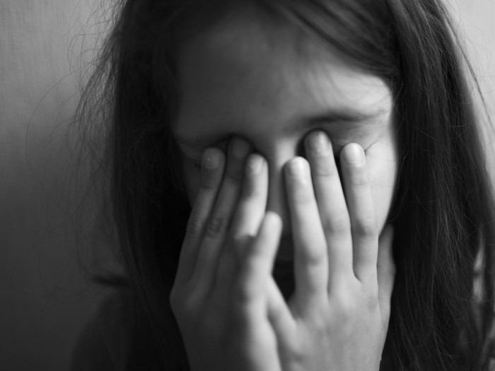 Little girl covers her face with hands isolated