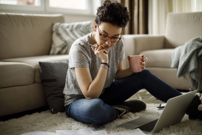 457207791 Woman sitting on sofa using laptop in her cozy loft apartment