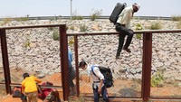 Beberapa pekerja dari Maharashtra melompati pagar untuk menuju jalan raya di Hyderabad, India pada Senin (4/5/2020). AP Photo/Mahesh Kumar A.