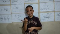 Widi, seorang santri tuna rungu, berdiri di depan gambarnya di sekolah asrama tuli Islam Darul Ashom.