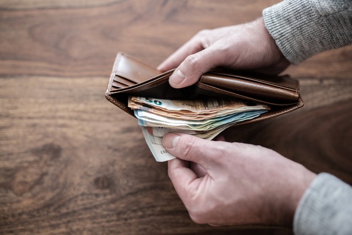 1091788026 close-up of person counting stack of paper cash in wallet