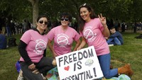Dengan membawa spanduk bertulis Freedom, para aksi masa terlihat tidak ada yang memakai alat pelindung diri. AP Photo/Kirsty Wigglesworth.