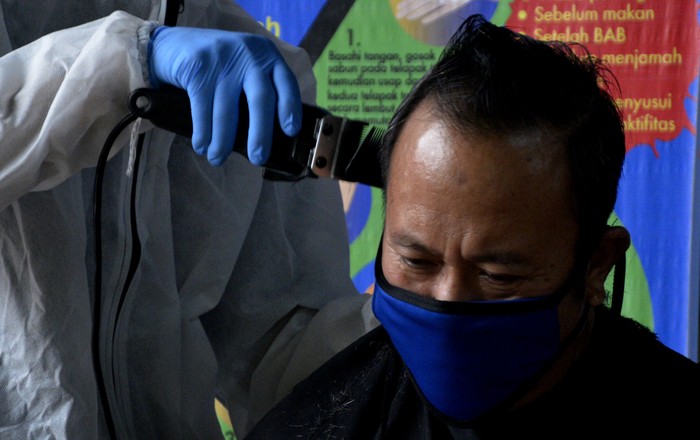 Mahasiswa Fakultas Teknologi Industri Universitas Muslim Indonesia (FTI UMI)  Makassar memangkas rambut seorang dokter sambil menggunakan Alat Pelindung Diri (APD) di Makassar, Sulawesi Selatan, Minggu (17/5/2020). Kegiatan itu diberikan kepada sejumlah dokter yang telah bertugas menangani pasien yang terjangkit virus COVID-19 selama dua bulan di rumah sakit. ANTARA FOTO/Abriawan Abhe/aww.