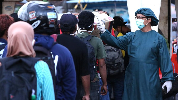 Petugas kesehatan memeriksa suhu tubuh para pemudik usai turun dari kapal di Pelabuhan Ketapang, Banyuwangi, Jawa Timur, Senin (18/5/2020). Pada H-6 arus mudik Idul Fitri dari Pulau Bali dengan tujuan Pulau Jawa di Pelabuhan Ketapang terpantau ramai penumpang pejalan kaki. ANTARA FOTO/Budi Candra Setya/wsj.